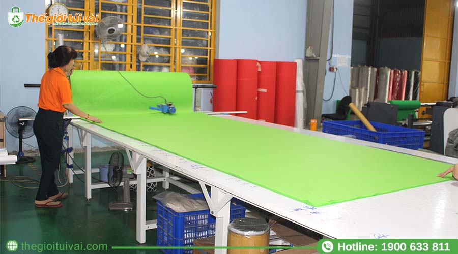 Thợ cắt vải đang sử dụng máy cắt đứng chuyên dụng