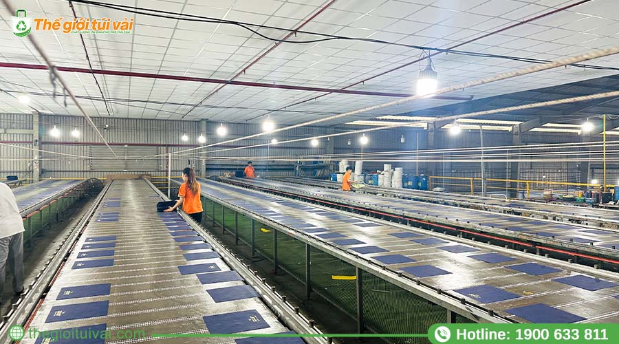 Thợ in đang thực hiện in lụa thủ công trên bàn in Thợ in đang thực hiện in lụa thủ công trên bàn in